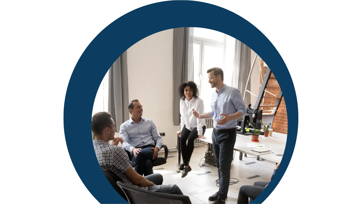 Four people talking in a bright office, two standing and two seated
