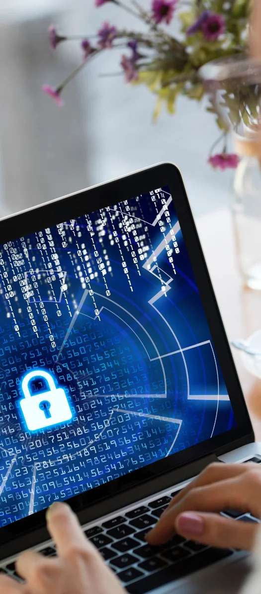 Hands typing on a laptop showing a glowing padlock over blue binary code